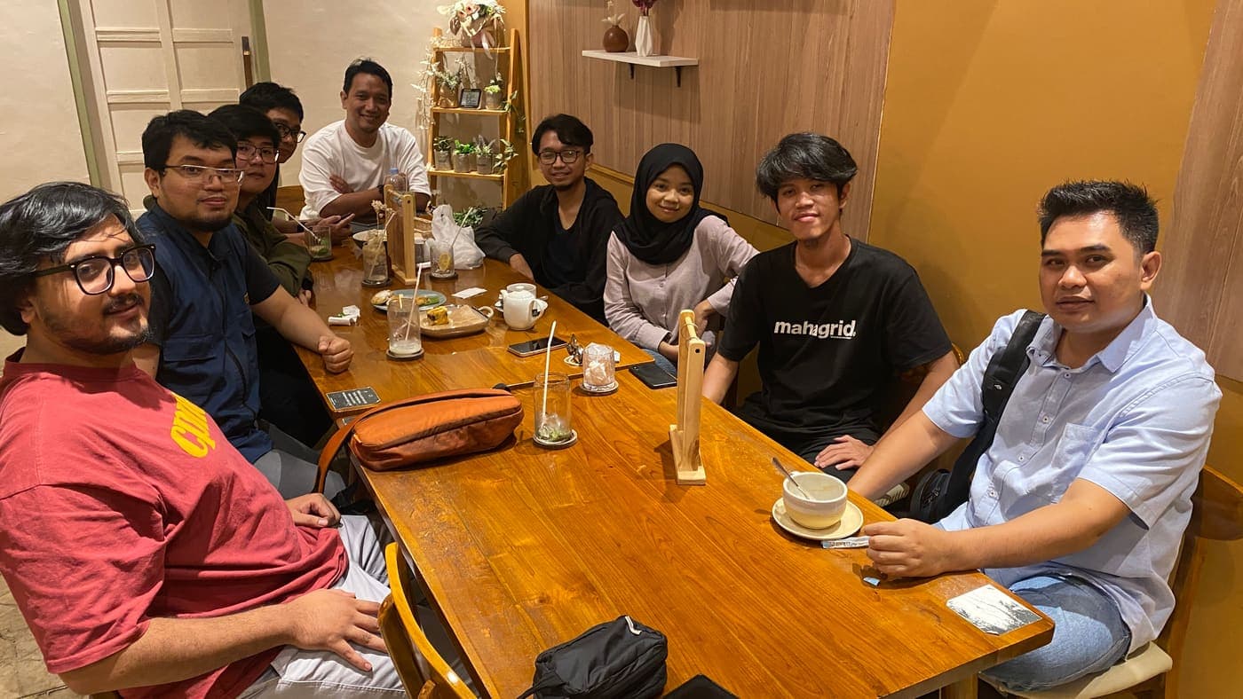 Anggota Tech Voice Indonesia duduk mengelilingi satu meja panjang di sebuah kafe saat meetup komunitas.