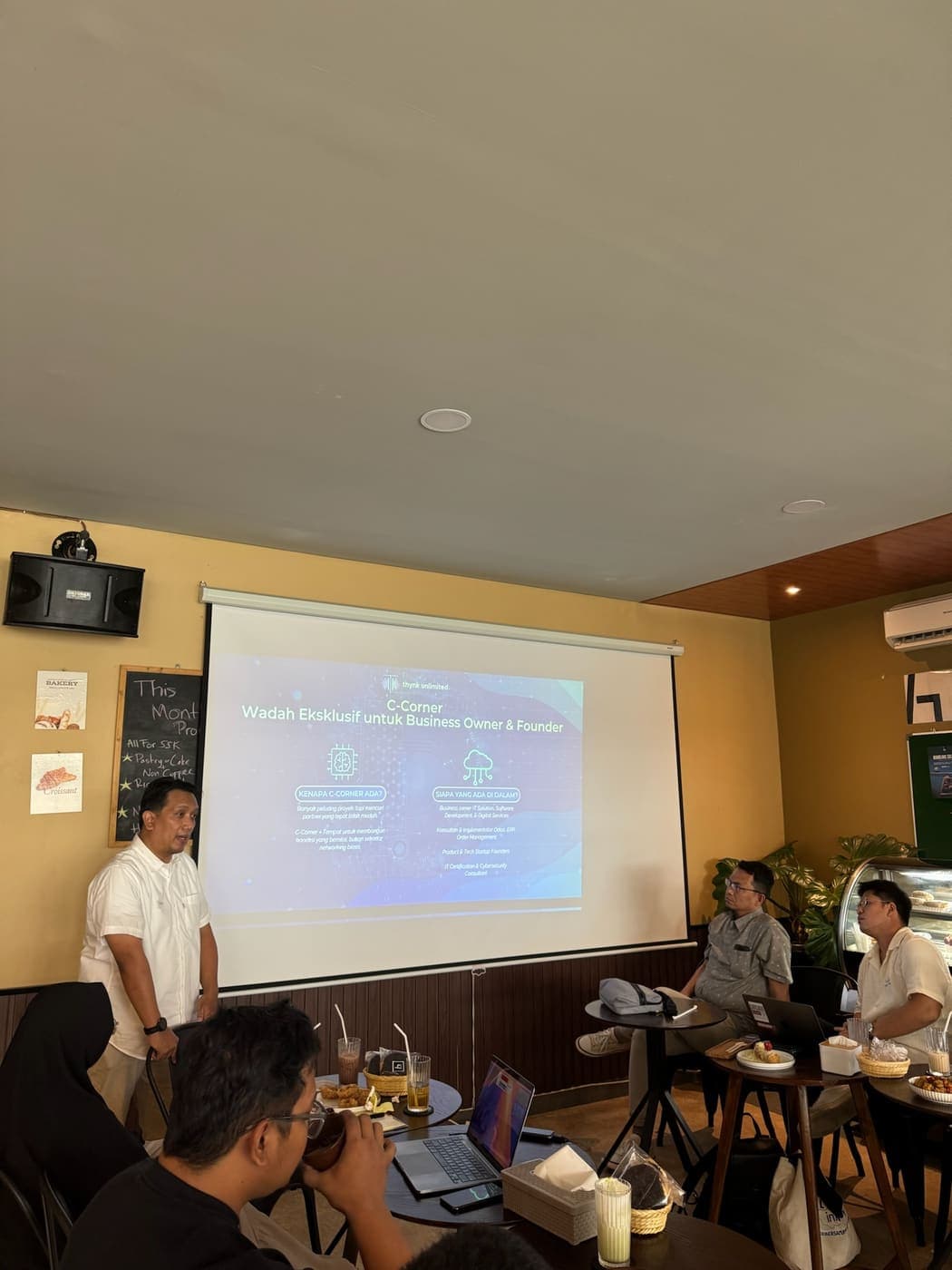 Seorang pembicara memaparkan materi di depan layar proyektor dalam sesi komunitas Tech Voice Indonesia.