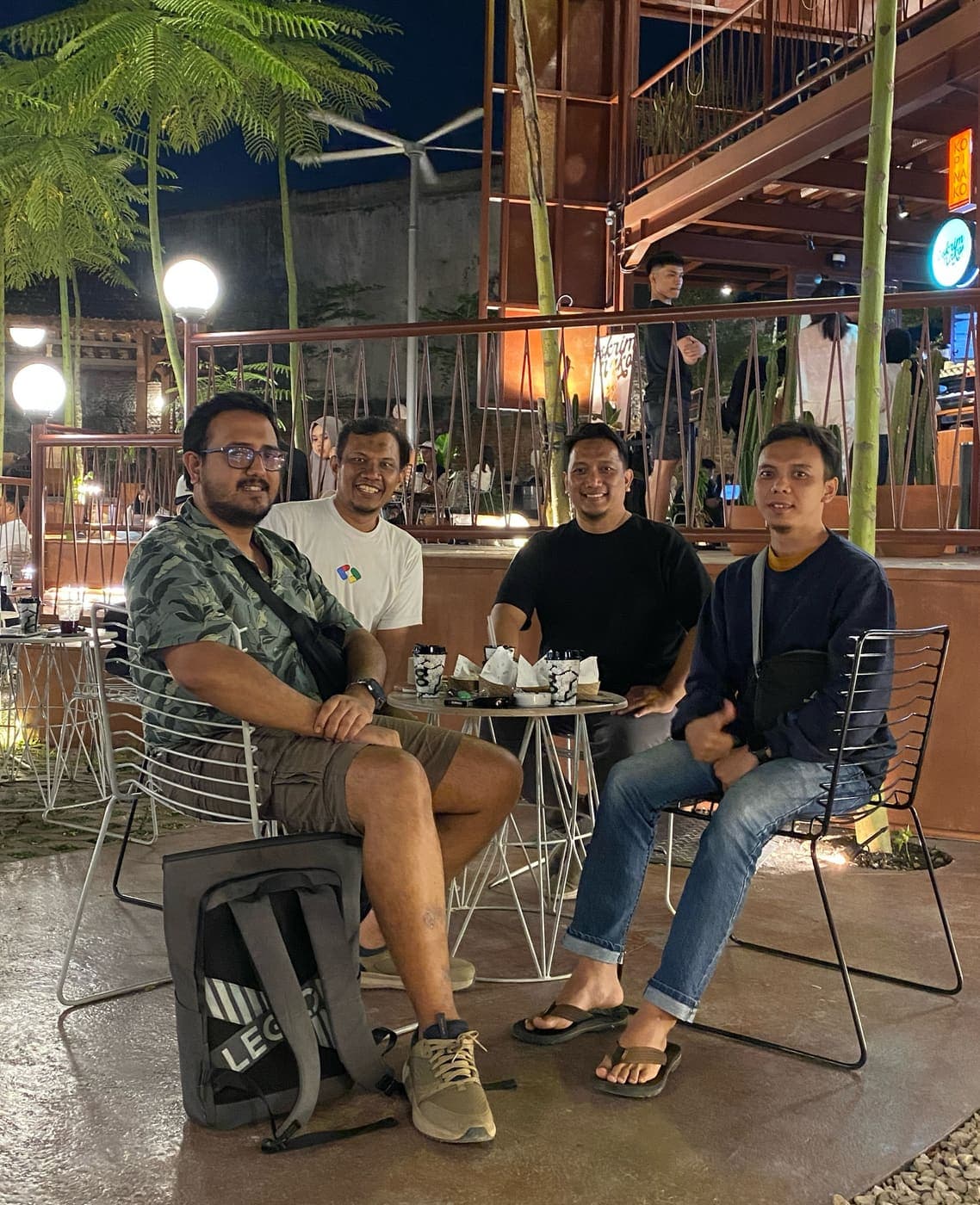 Empat anggota Tech Voice Indonesia mengobrol di meja kafe terbuka pada malam hari.